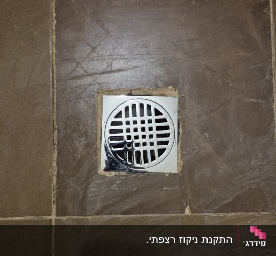 רשת ניקוז מנירוסטה מותקנת ברצפת אריחים לאחר עבודת אינסטלציה